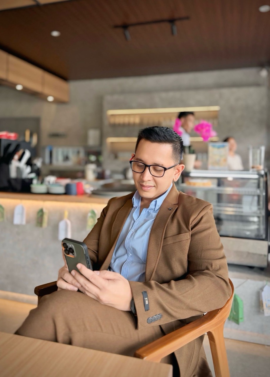 Reinheart duduk di kafe sambil melihat ponsel