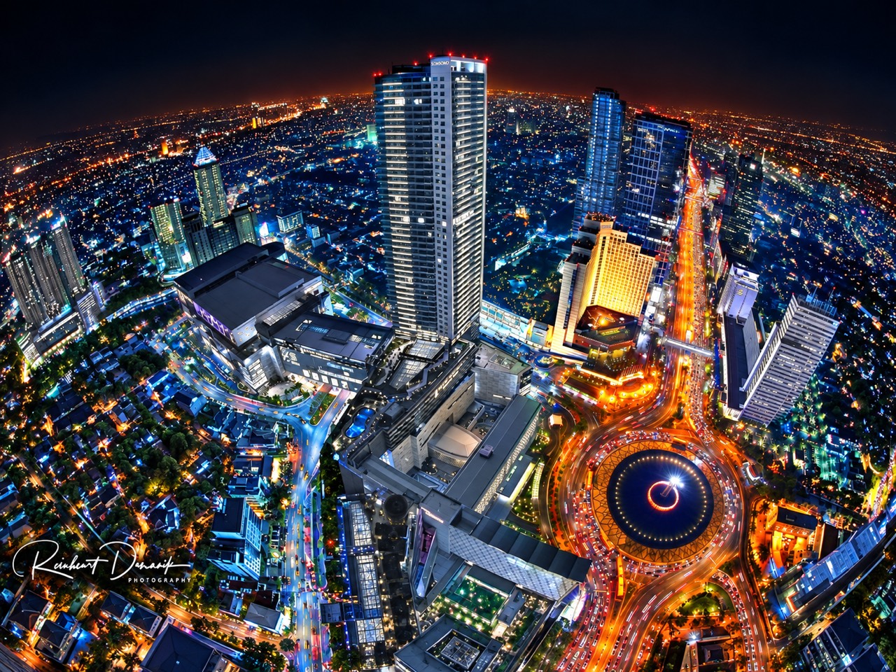 Panorama kota malam dengan gedung tinggi dan bundaran bercahaya